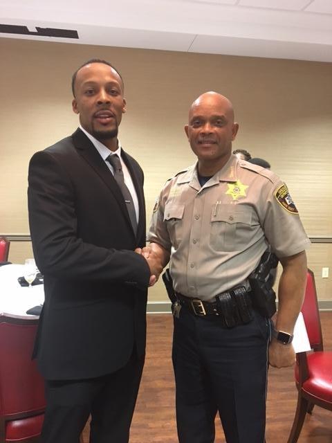 Man in suit shaking Sheriff's hand