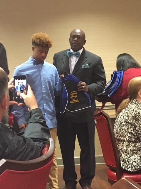 Man holding a Wildcats backpack, standing next to a young man in a bowtie